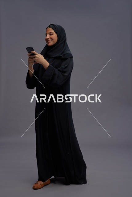 امرأة سعودية بالعباءة تستخدم الهاتف الذكي في الاستوديو