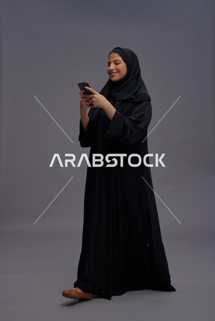 امرأة سعودية بعباءة تستخدم الهاتف الذكي في الاستوديو