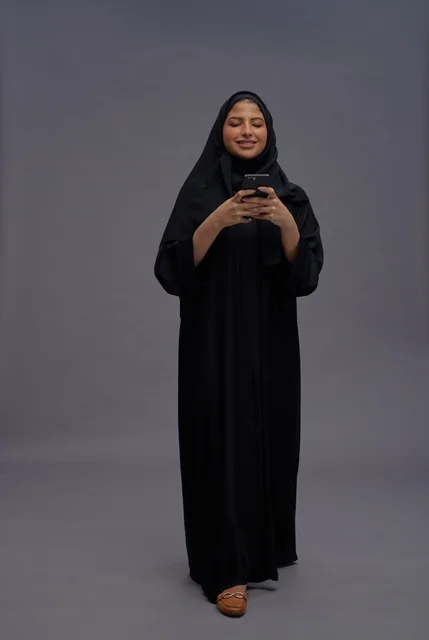 Saudi Woman in Abaya Using Smartphone in Studio