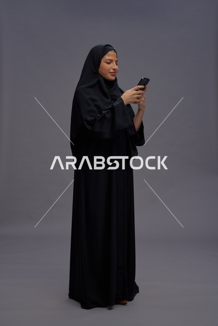 امرأة سعودية بالعباءة تستخدم هاتف ذكي في استوديو