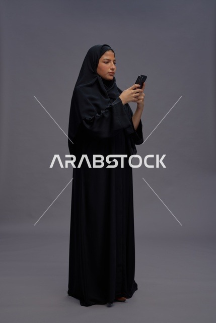 امرأة سعودية بالعباءة تستخدم الهاتف الذكي في الاستوديو