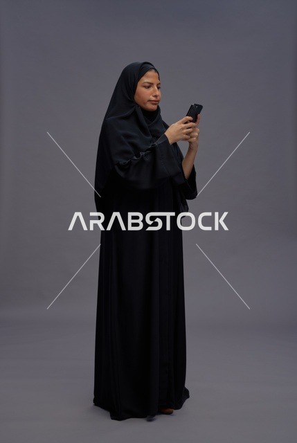 امرأة سعودية بالعباءة تستخدم الهاتف في الاستوديو