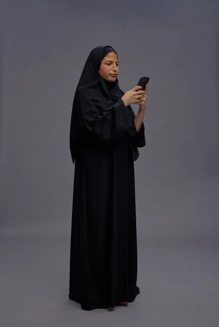 امرأة سعودية بالعباءة تستخدم الهاتف في الاستوديو