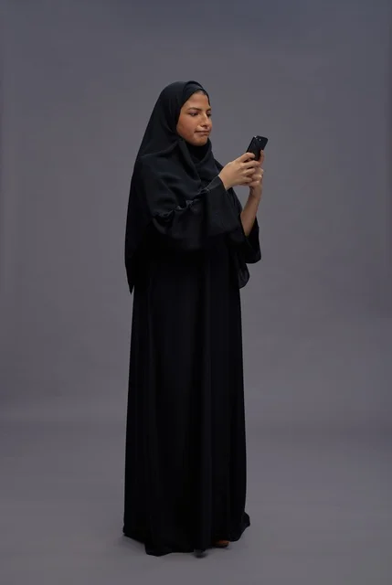 Saudi Woman in Abaya Using Smartphone in Studio