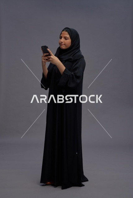 امرأة سعودية بعباءة سوداء تستخدم الهاتف الذكي