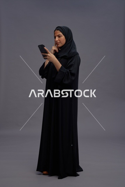 امرأة سعودية بعباءة تستخدم الهاتف الذكي في استوديو