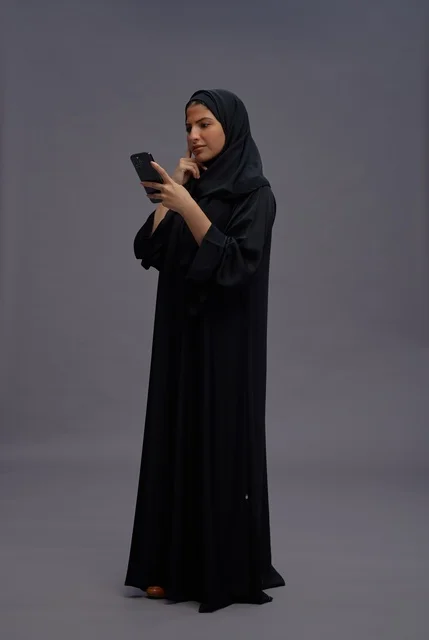 امرأة سعودية بعباءة تستخدم الهاتف الذكي في استوديو امرأة سعودية بعباءة تستخدم الهاتف الذكي في استوديو