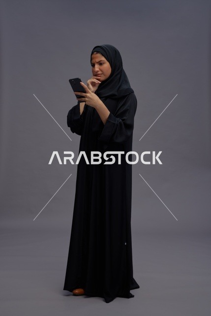 امرأة سعودية بالعباءة تستخدم الهاتف الذكي في استوديو