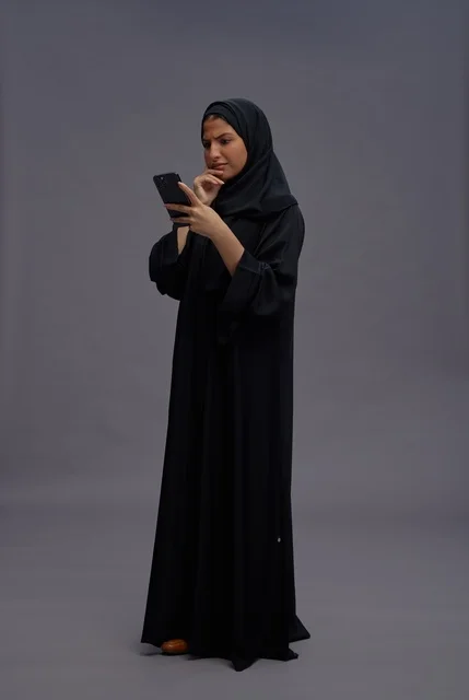 Saudi Woman in Abaya Using Smartphone in Studio