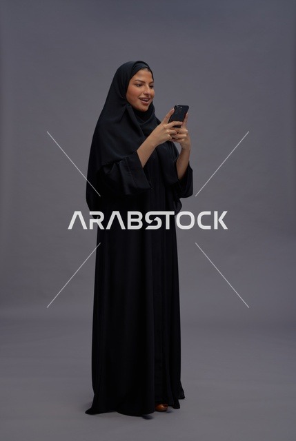 امرأة سعودية بعباءة سوداء تستخدم هاتف ذكي
