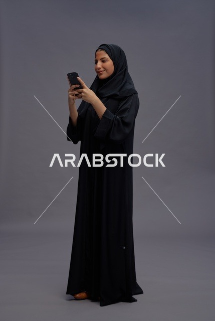 امرأة سعودية بالعباءة تستخدم الهاتف الذكي في الاستوديو