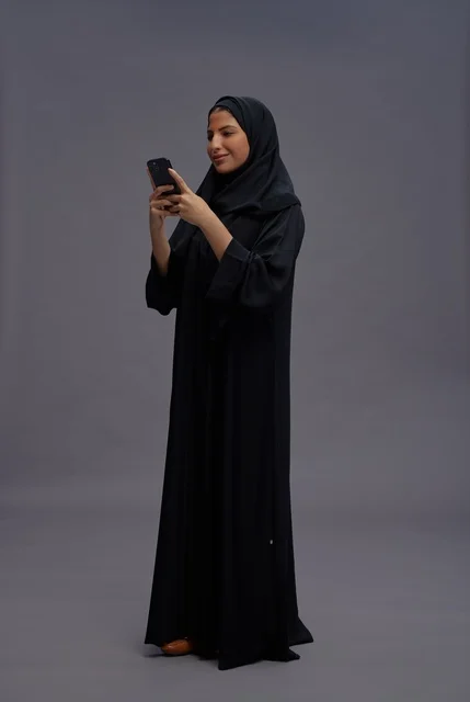 امرأة سعودية بالعباءة تستخدم الهاتف الذكي في الاستوديو
