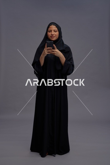 امرأة سعودية بعباءة تستخدم الهاتف الذكي في الاستوديو