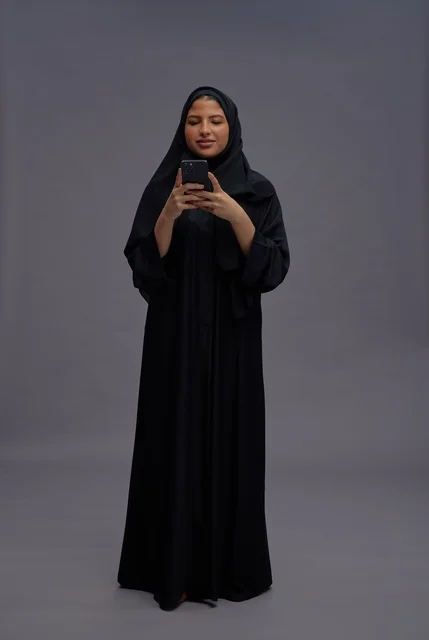 Saudi Woman in Abaya Using Smartphone in Studio