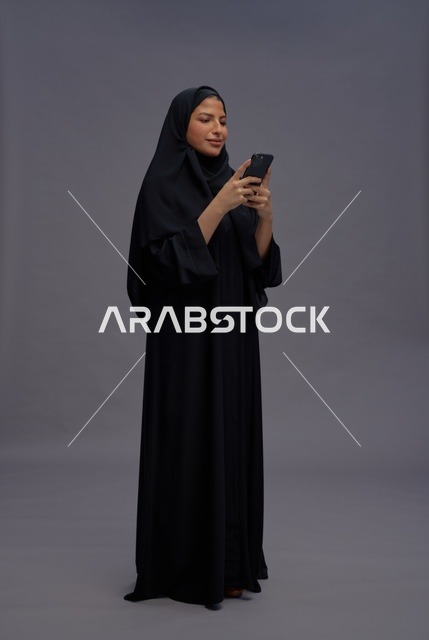 امرأة سعودية بعباءة سوداء تستخدم هاتف ذكي