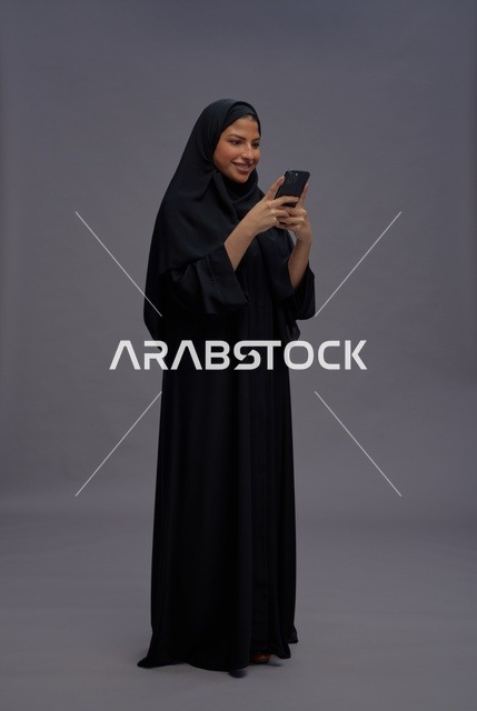 امرأة سعودية بالعباءة تستخدم الهاتف الذكي في الاستوديو