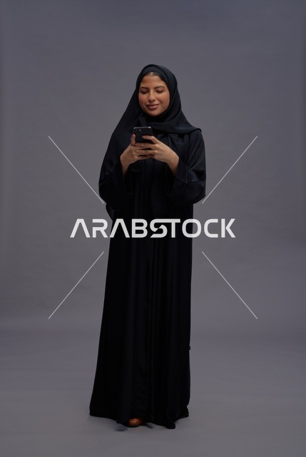امرأة سعودية بالعباءة تستخدم الهاتف الذكي