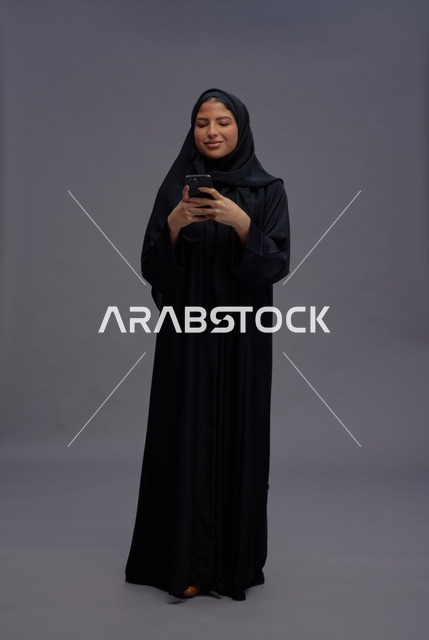 امرأة سعودية بالعباءة تستخدم الهاتف الذكي في الاستوديو