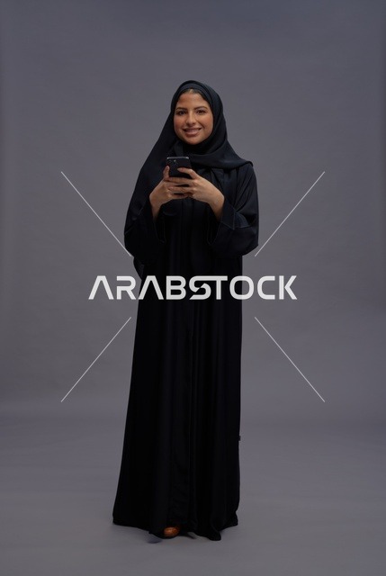 امرأة سعودية بعباءة سوداء تستخدم الهاتف الذكي