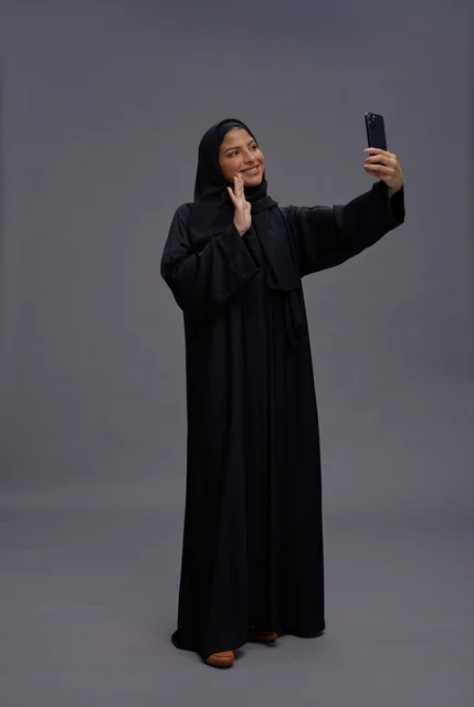امرأة سعودية بالعباءة تلتقط سيلفي بالهاتف الذكي