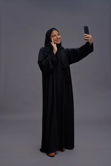 امرأة سعودية بالعباءة تلتقط سيلفي بالهاتف الذكي