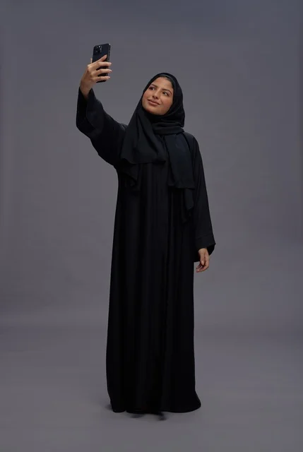 امرأة سعودية بالعباءة تلتقط سيلفي بالهاتف الذكي