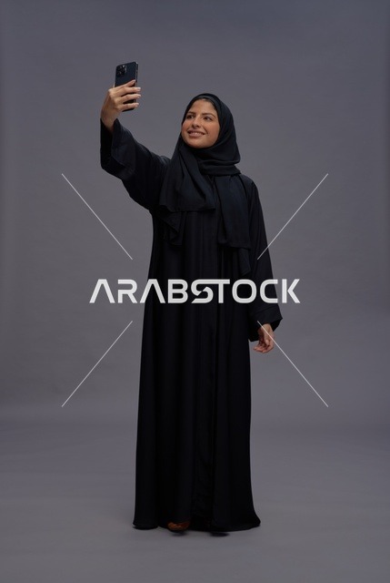 امرأة سعودية تلتقط صورة سيلفي بالهاتف الذكي في استوديو