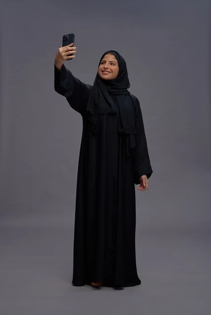 امرأة سعودية تلتقط صورة سيلفي بالهاتف الذكي في استوديو