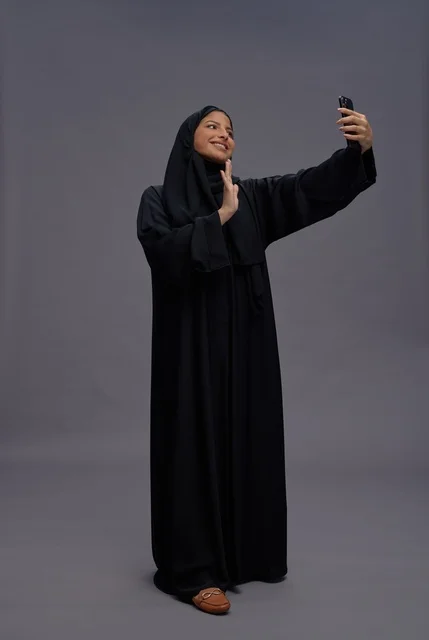 امرأة سعودية بالعباءة السوداء تلتقط سيلفي بالهاتف