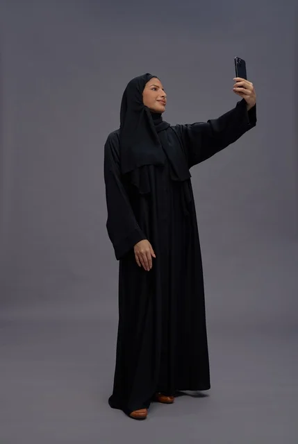 امرأة سعودية تلتقط سيلفي بالهاتف في استوديو