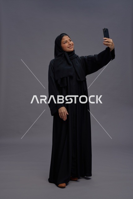 امرأة سعودية تلتقط سيلفي بالهاتف الذكي والعباءة