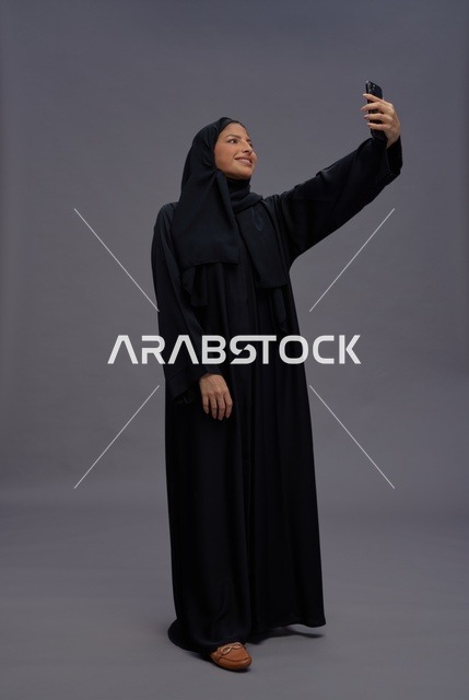 امرأة سعودية تلتقط صورة سيلفي بهاتف ذكي في استوديو