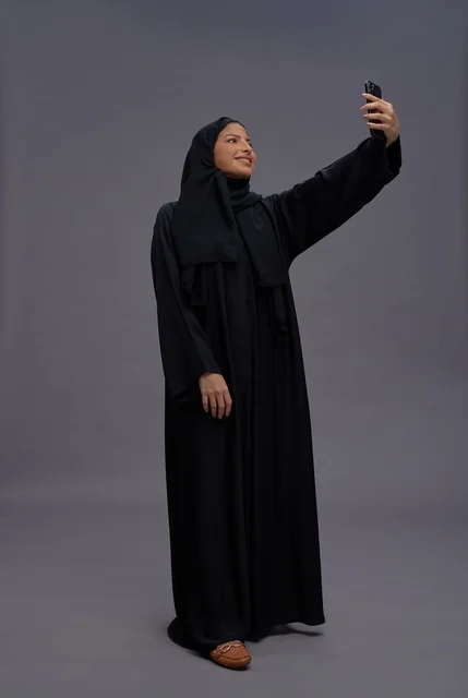 Saudi Woman Taking Selfie with Smartphone in Studio