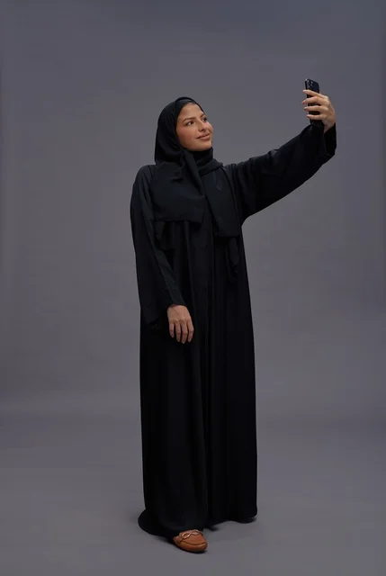امرأة سعودية بعباءة سوداء تلتقط سيلفي بالهاتف