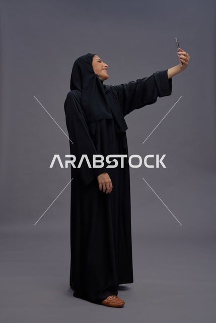 امرأة سعودية بالعباءة تلتقط صورة سيلفي بالجوال