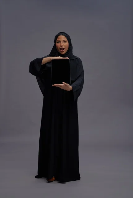 Saudi Woman in Abaya Holding Blank Tablet with Surprise