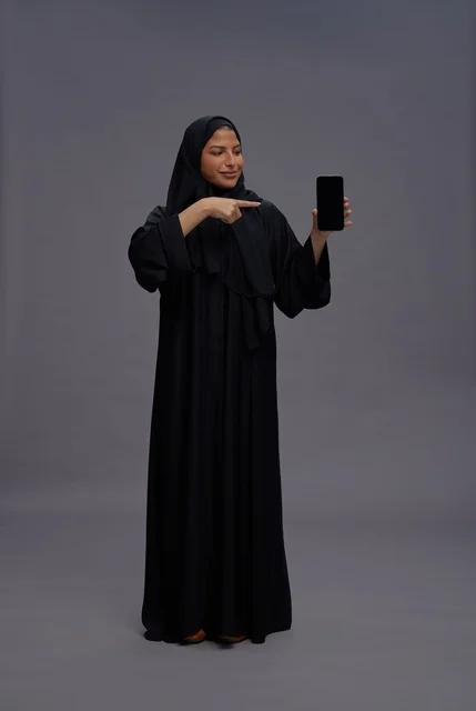 Saudi Woman in Abaya Pointing to Blank Smartphone