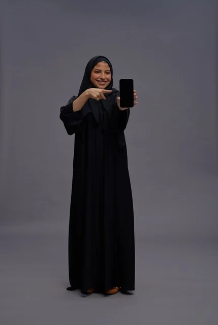 Saudi Woman in Abaya Pointing at Smartphone Screen