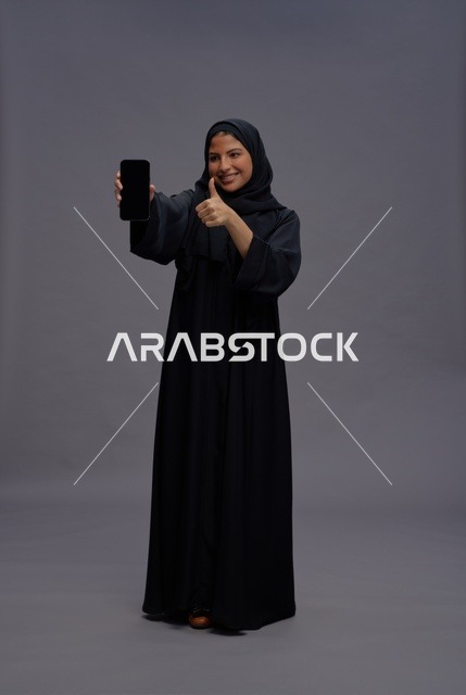 Saudi Woman with Smartphone and Thumbs Up Studio Shot