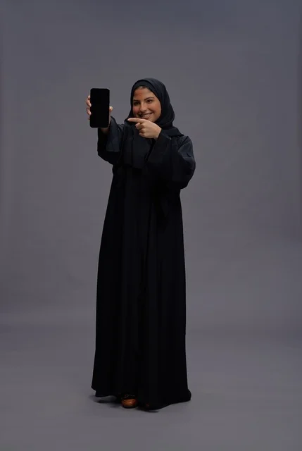 Saudi Woman in Abaya Pointing to Smartphone Screen