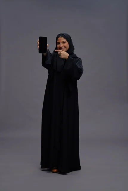 Saudi Woman in Abaya Pointing at Smartphone Screen