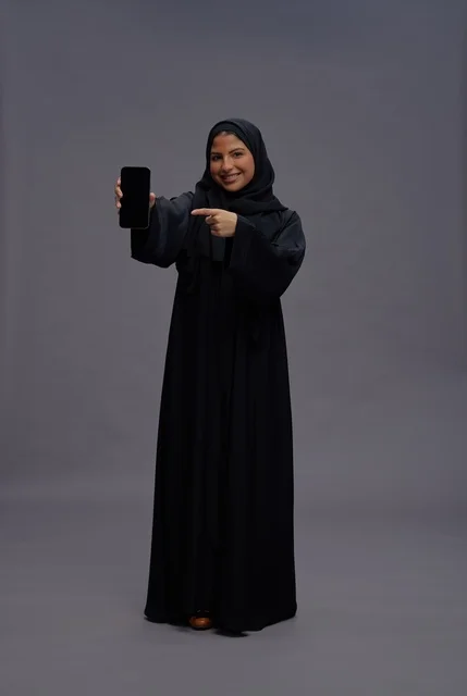 Saudi Woman in Abaya Holding Smartphone with Blank Screen