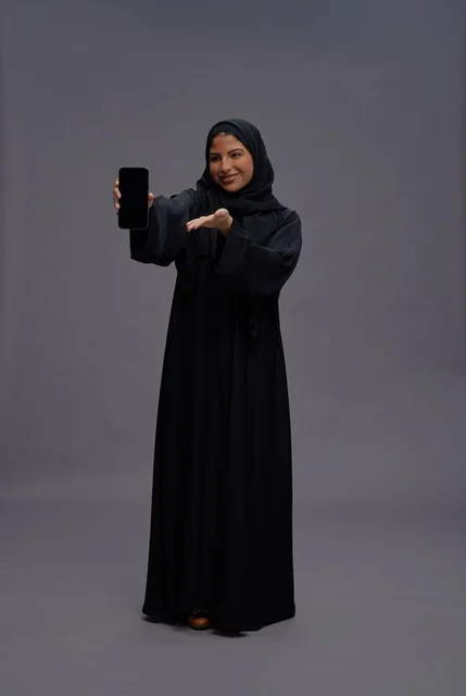Saudi Woman in Abaya Holding Smartphone with Blank Screen