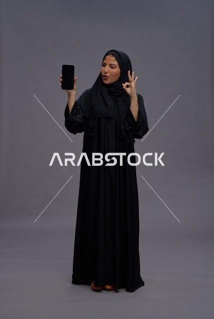 Saudi Woman Holding Blank Smartphone with OK Gesture