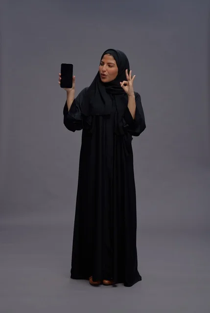 Saudi Woman Holding Blank Smartphone with OK Gesture