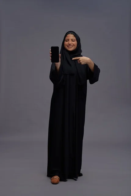 Saudi Woman in Abaya Pointing at Smartphone Screen