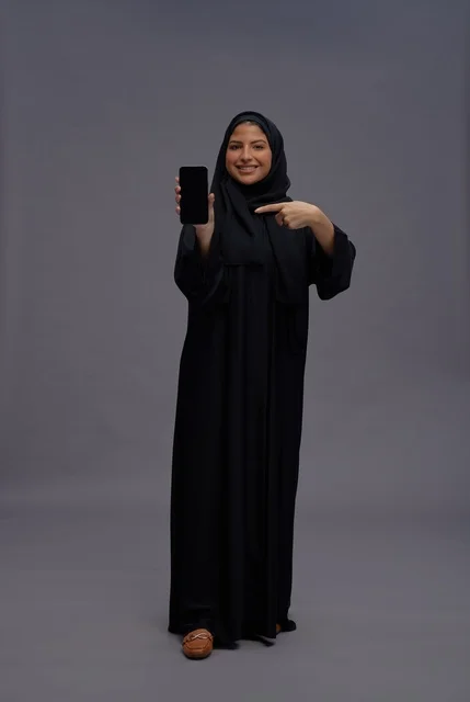 Saudi Woman in Abaya Holding Smartphone with Blank Screen