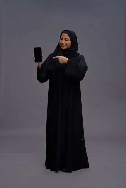 Saudi Woman in Abaya Pointing at Blank Smartphone Screen
