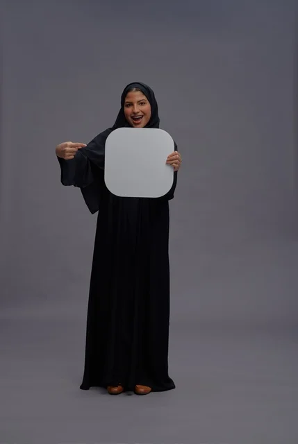 امرأة سعودية بالعباءة تحمل لوحة بيضاء فارغة للإعلان