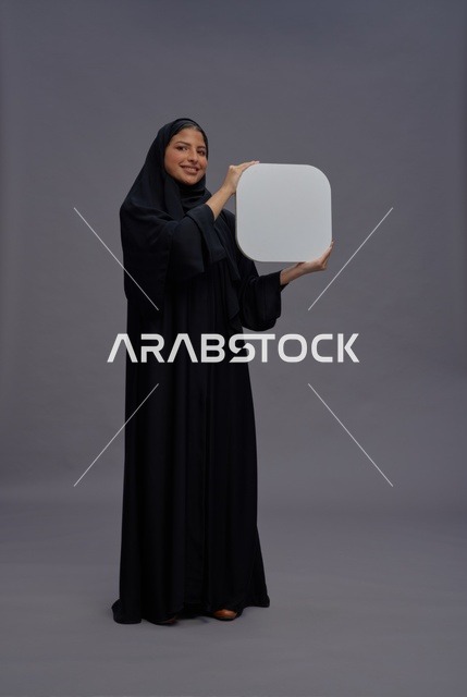 امرأة سعودية بالعباءة تمسك لوحة بيضاء فارغة